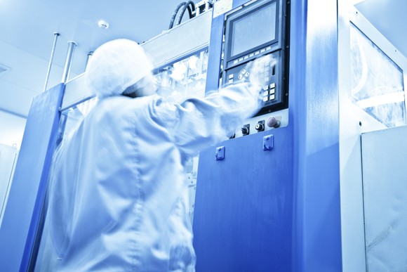 A technician operating inside of a pharmaceutical factory.