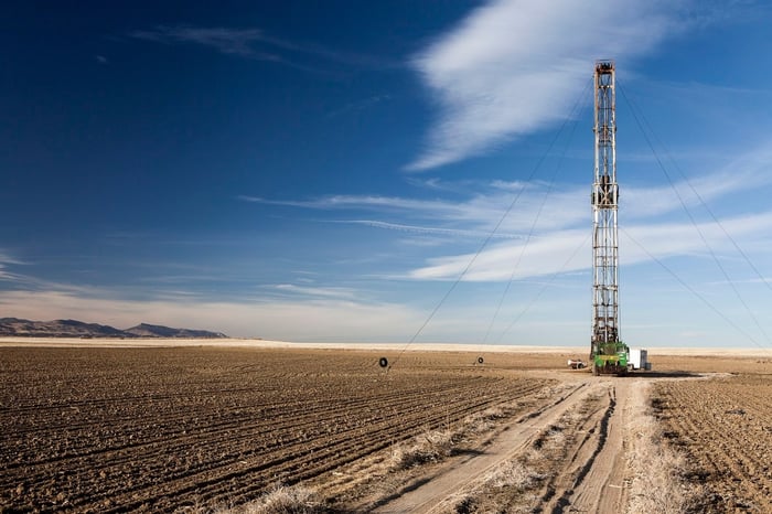 A drilling rig in a barren setting with a bright blue big open sky.