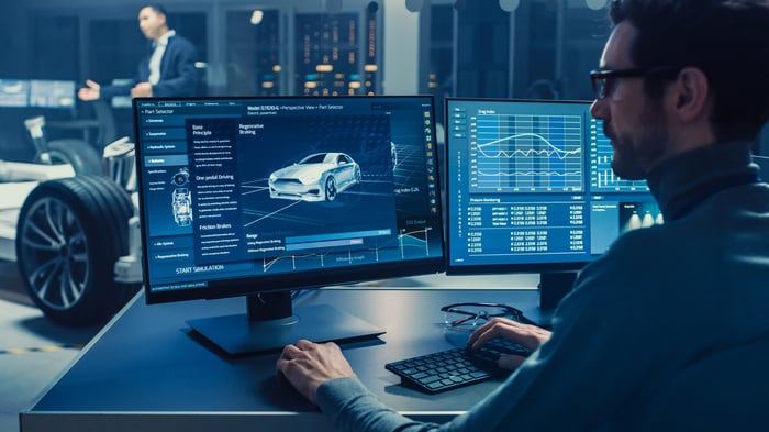 Person looking at computer screens showing a car diagram and charts.