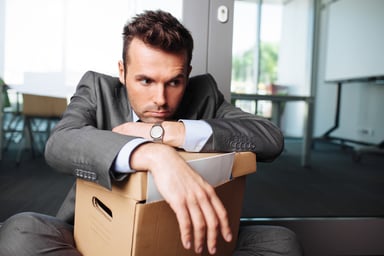 young businessman with desk packed into cardboard box fired from job terminated worker layoff laid off