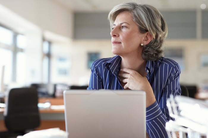 A person sitting in front of a laptop and looking to the side.