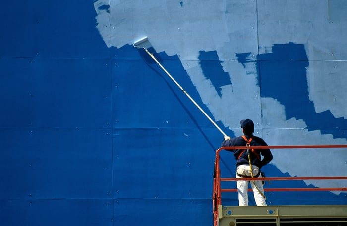 A man painting over a billboard.