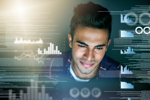 Developer looking at screen with graph icons around him.