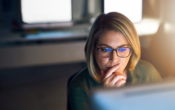 Person with glasses looking at a computer screen.