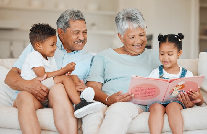 Two adults reading a book to children.
