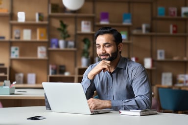 person sitting at a desk looking at a laptop and smiling