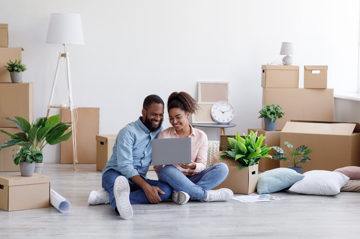 Two individuals looking at a laptop together while sitting on the floor.