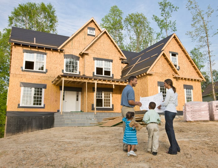 A family looks at a house that is under construction.