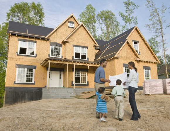A family looks at a house that is under construction.