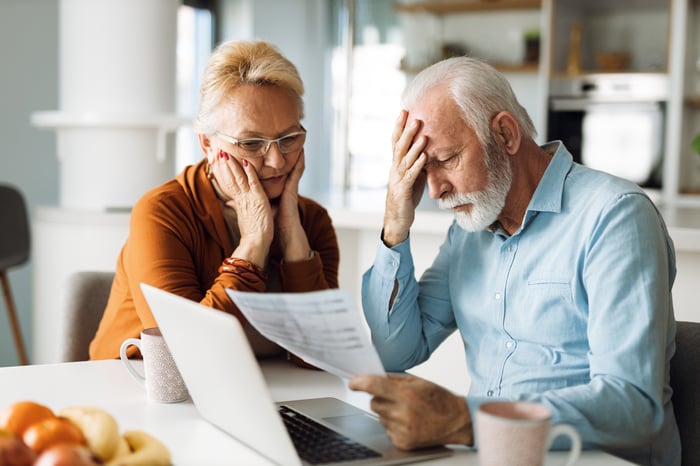 Two people look at paperwork with worried looks on their faces.