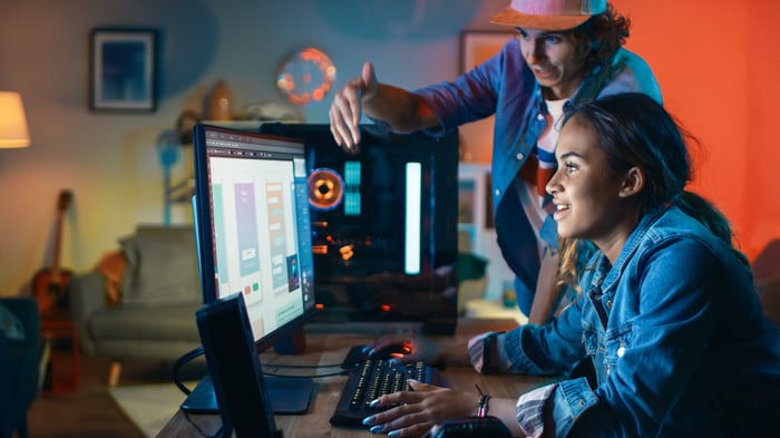 Two developers design a mobile app on a computer.