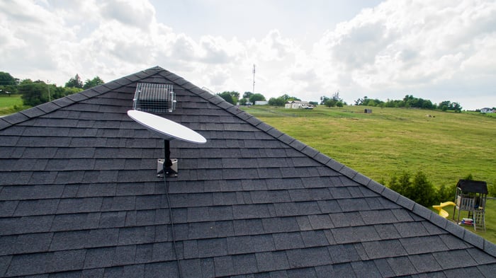 Satellite dish on a rooftop in the countryside.