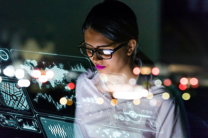 A person looking at graphs and charts on a futuristic see-through interface.