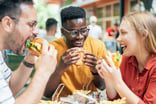 Friends eating burgers and fries and have fun in outdoor restaurant