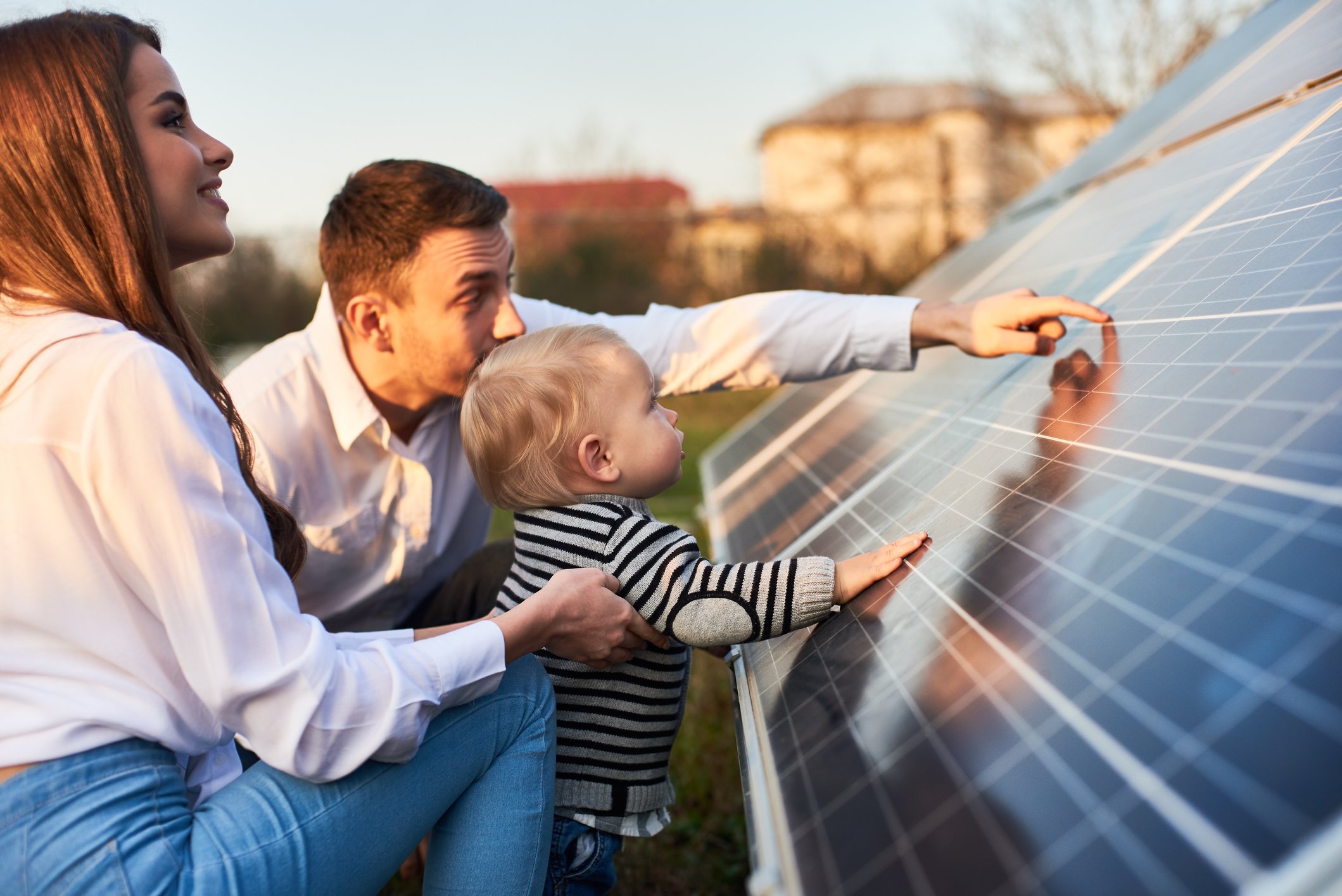 Two adults and a baby touching a solar panel array