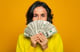 Young Woman holding a lot of money -- GettyImages-1249955556