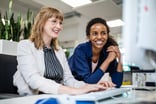 Two_happy_female_colleagues_working_on_a_computer