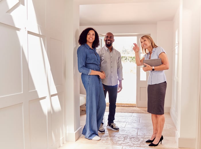 A realtor showing a brightly lit, empty home to a couple.