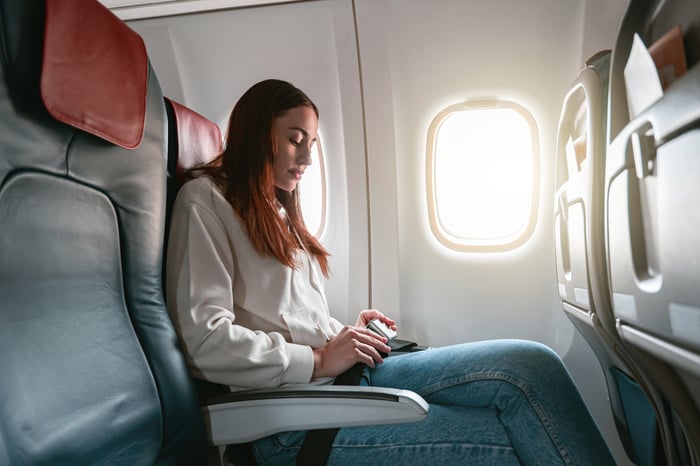 A passenger buckles their seatbelt on an airplane.