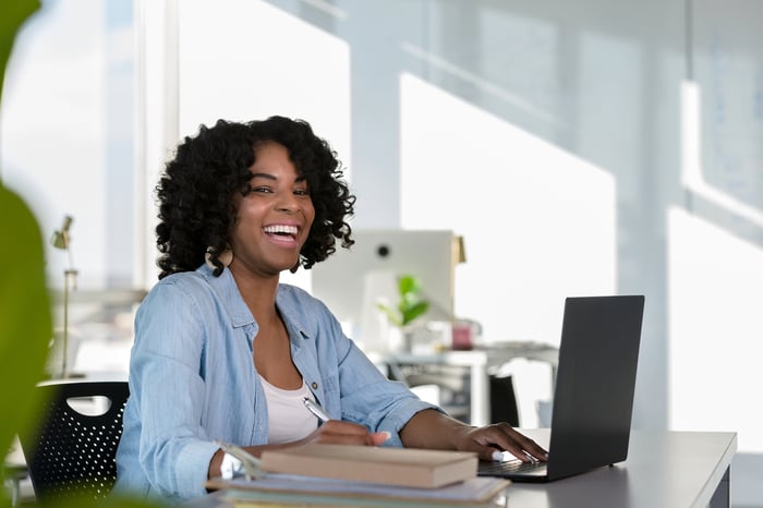 A person smiling while working on a laptop computer.