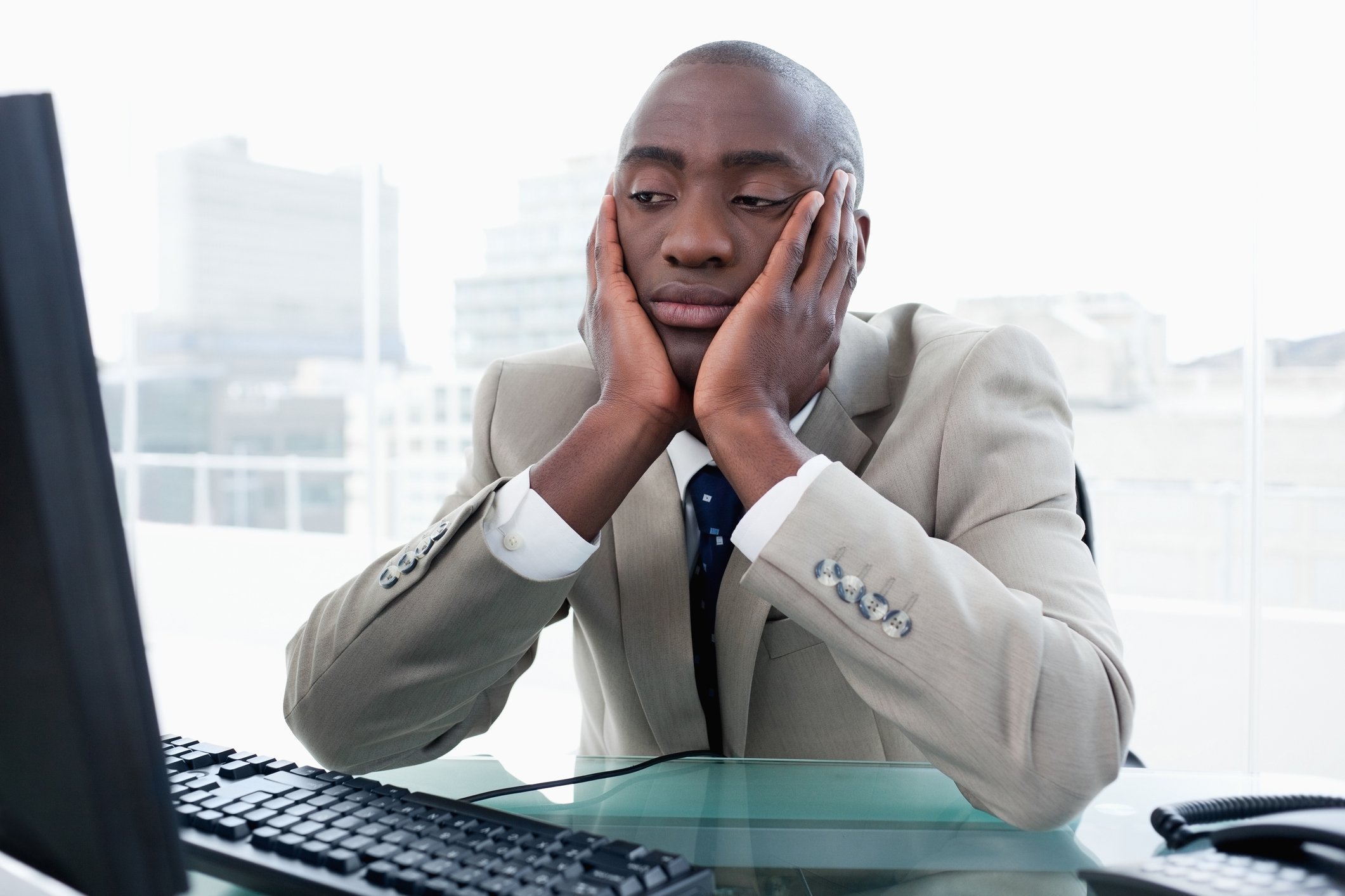 man in suit staring at computer with bored expression