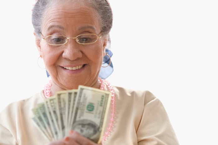 A smiling person looking at cash.