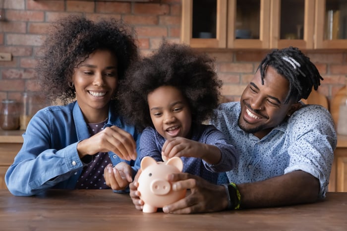 Parents using a piggy bank to teach child about money.