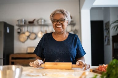Senior woman baking_A smiling person holding a rolling pin_GettyImages-1356378190