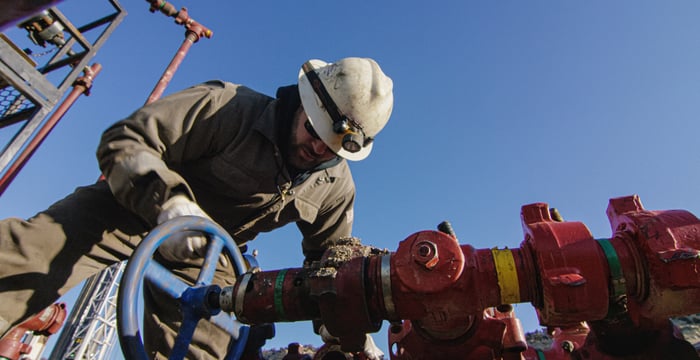 Oilfield worker looking at a pipe. 