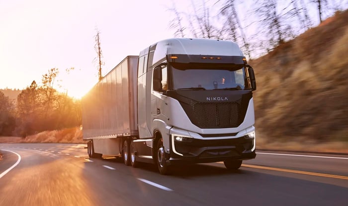 A Nikola Tre FCEV, an electric semi truck powered by a hydrogen fuel cell, towing a trailer uphill.