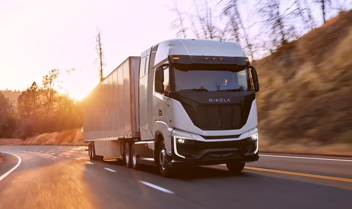 A Nikola Tre FCEV, an electric semi truck powered by a hydrogen fuel cell, towing a trailer uphill. 