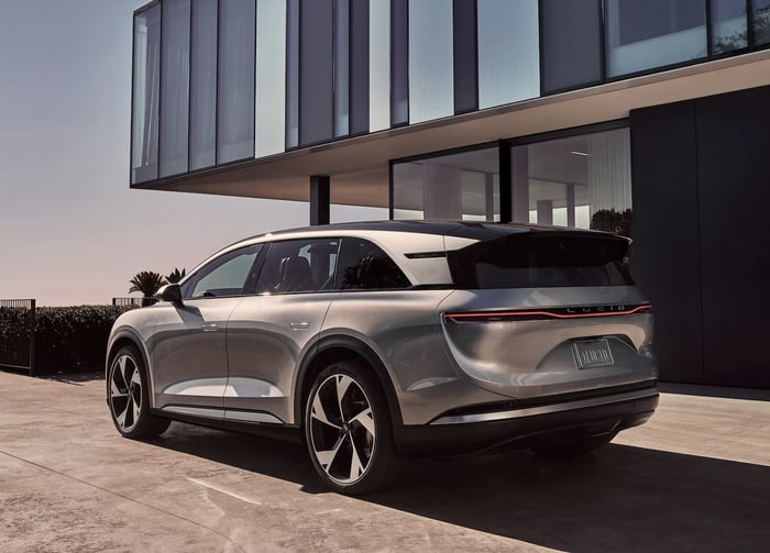 A Lucid Gravity, a big electric luxury SUV, in front of a modern office building. 