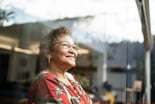 older person looking out a window and smiling
