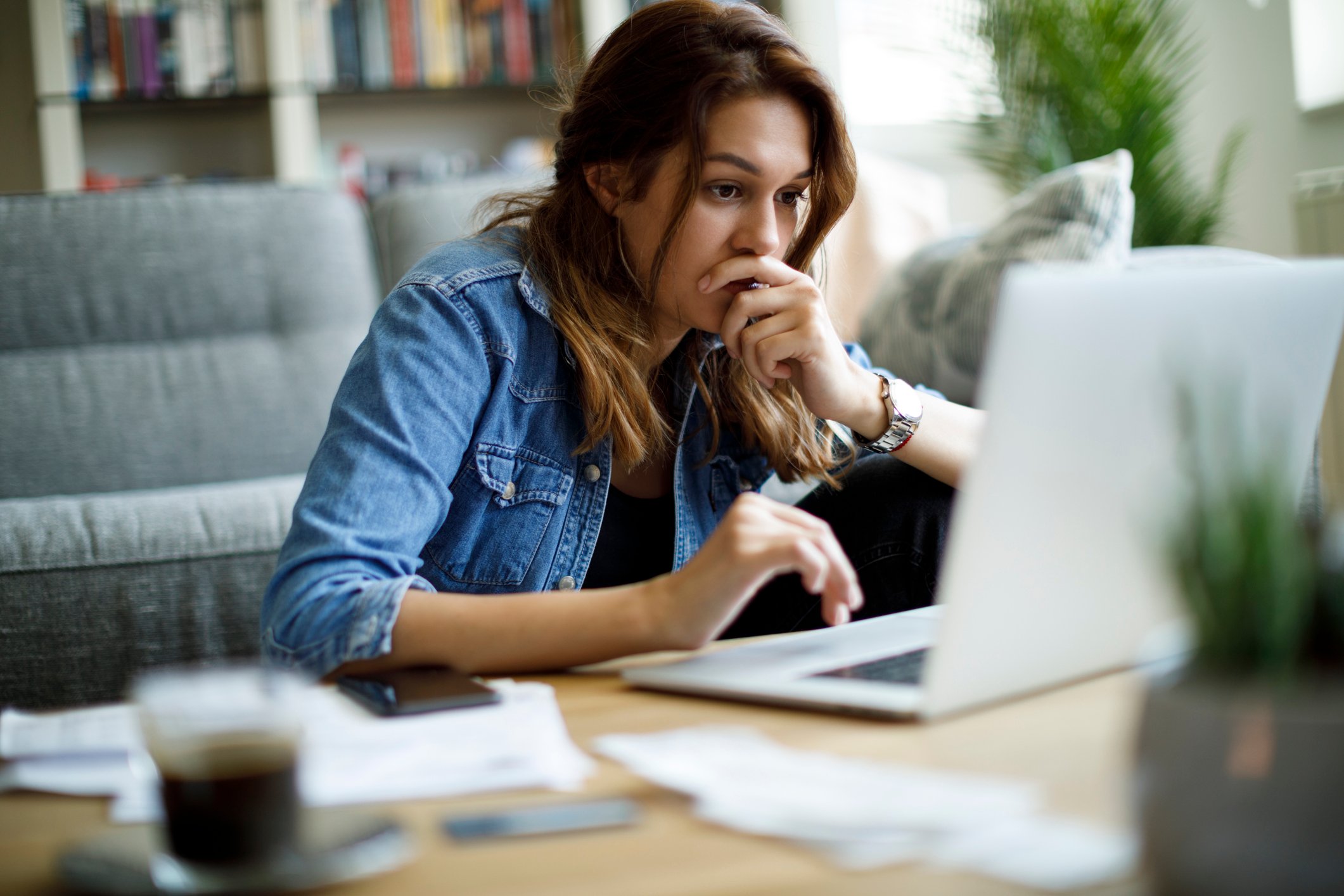 Investor looks worried at computer in a living room setting