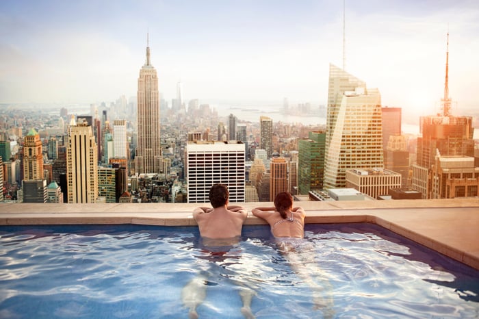 A couple in a rooftop pool looking at the New York skyline.