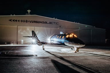 VSS Imagine with hangar in the background at night. IS Virgin Galactic.