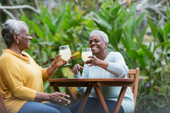 Two smiling people toasting each other.