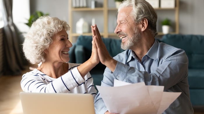 Two smiling people giving each other a high five.