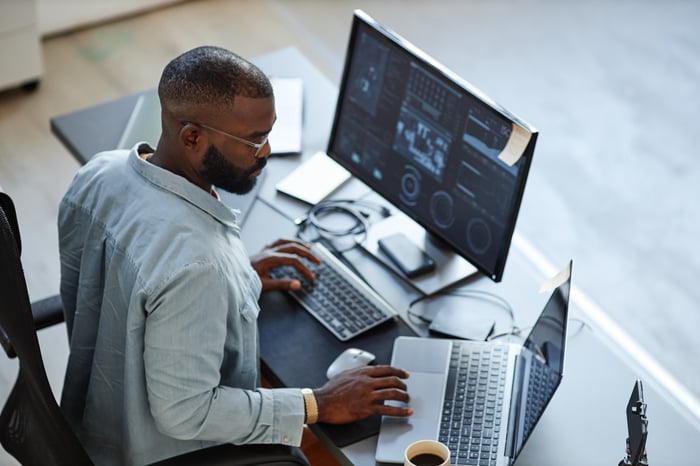 Person reviewing charts on multiple computer monitors.