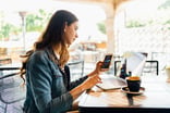 person sitting at a desk looking at laptop and phone