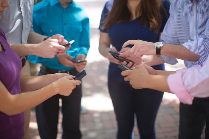 A group of people standing and holding their smartphones.