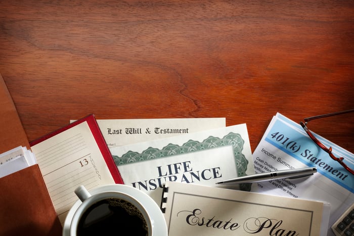 A collection of estate planning documents laid out on a wooden table with a cup of coffee.