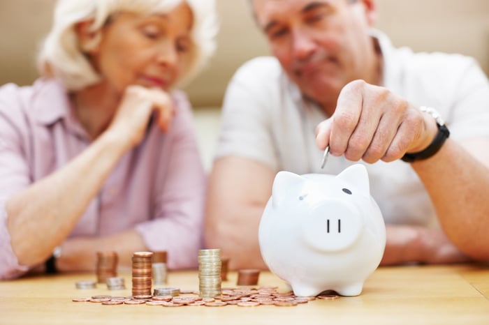 A couple saving coins in a piggy bank.