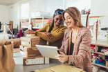 two people with packages looking at a tablet