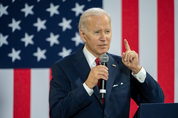Joe Biden delivering remarks while standing in front of a large American flag.