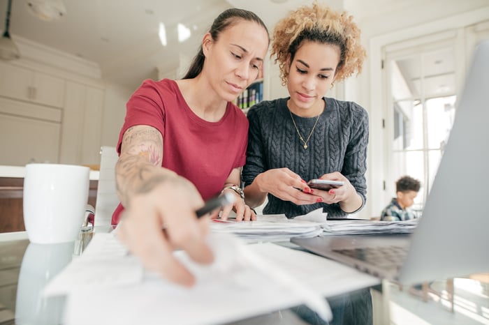 Two people, with one holding a calculator, looking at documents together.