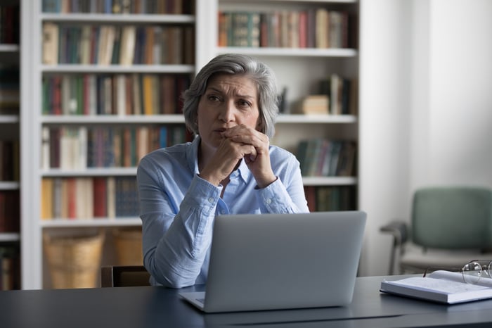 A person at a laptop with a serious expression.