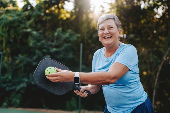 Someone is playing pickleball and smiling.