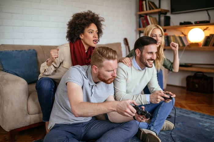 Four friends play a video game in a living room.