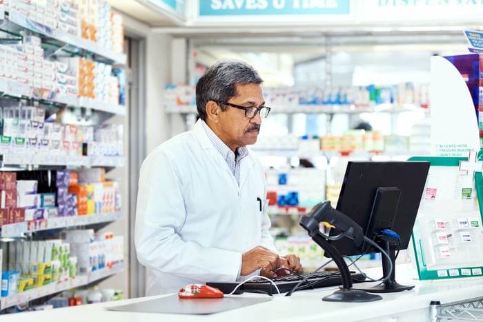 A pharmacist working at a computer on a counter.